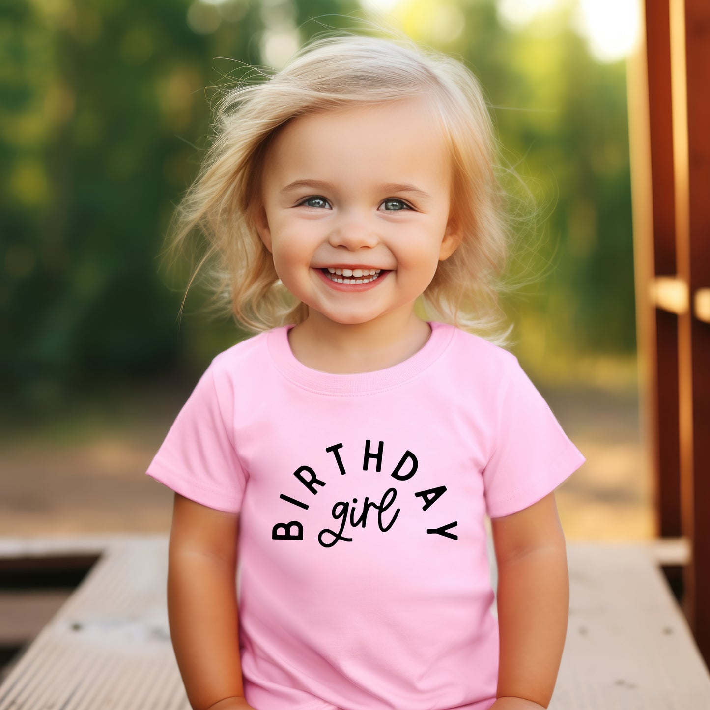 Child wearing a pink 'Birthday Girl' shirt outdoors