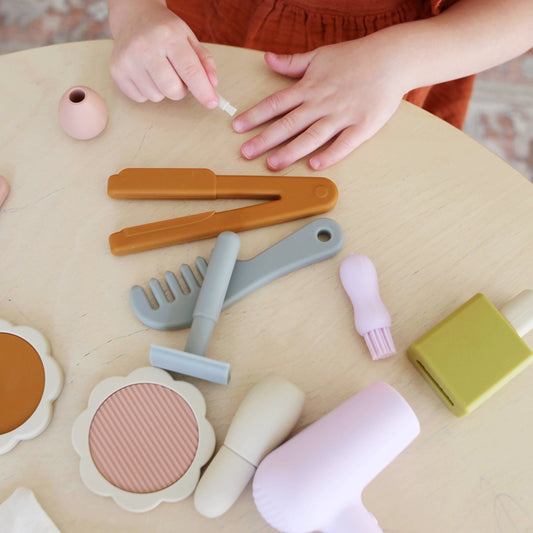 Child playing with toy makeup and hairbrushes on a table