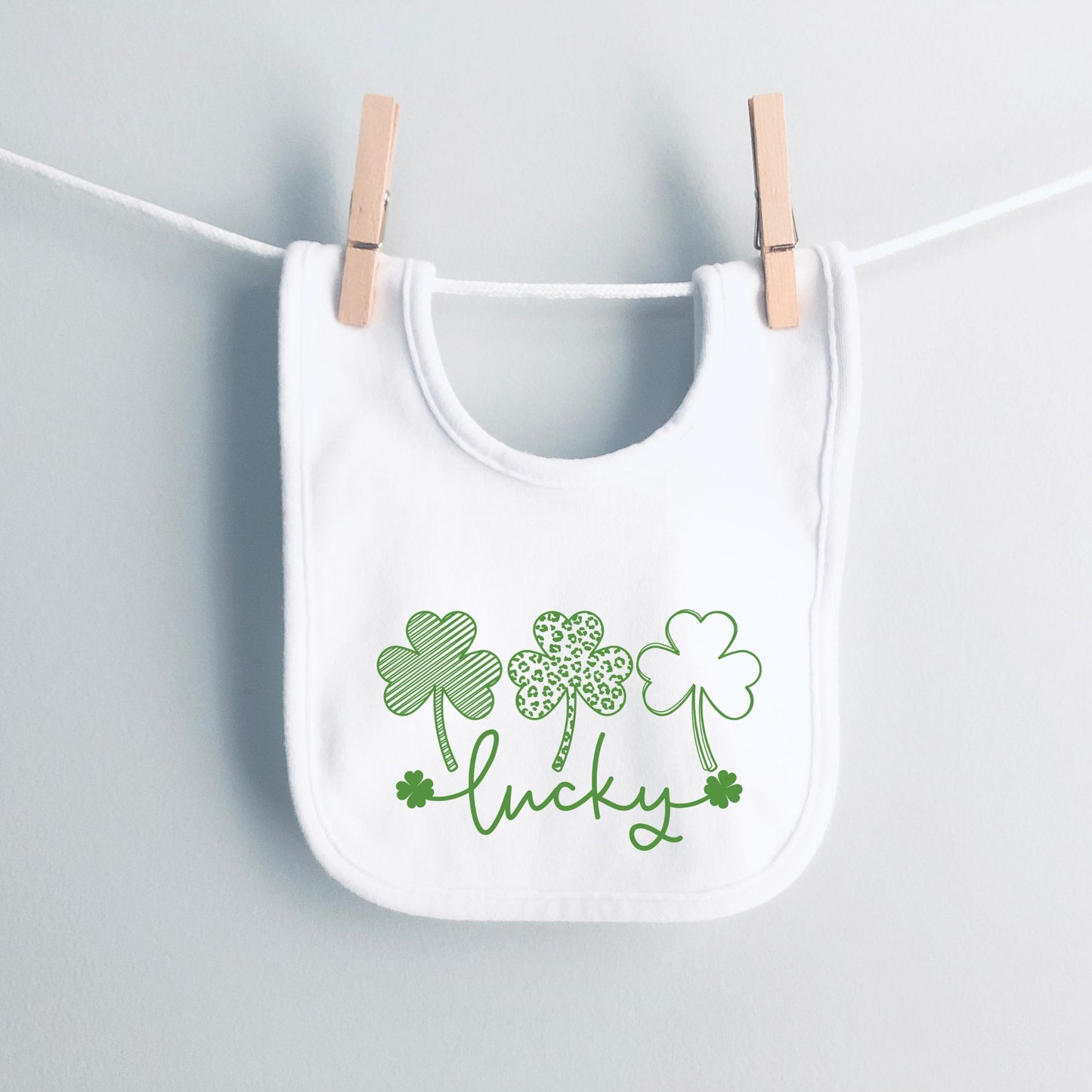 White bib with green shamrock design and 'lucky' text on a white background