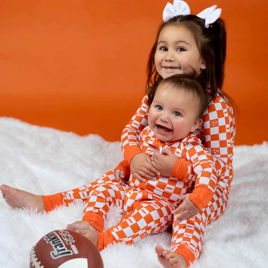 Baby wearing orange and white checkerboard bamboo convertible footie pajamas for fall sleep