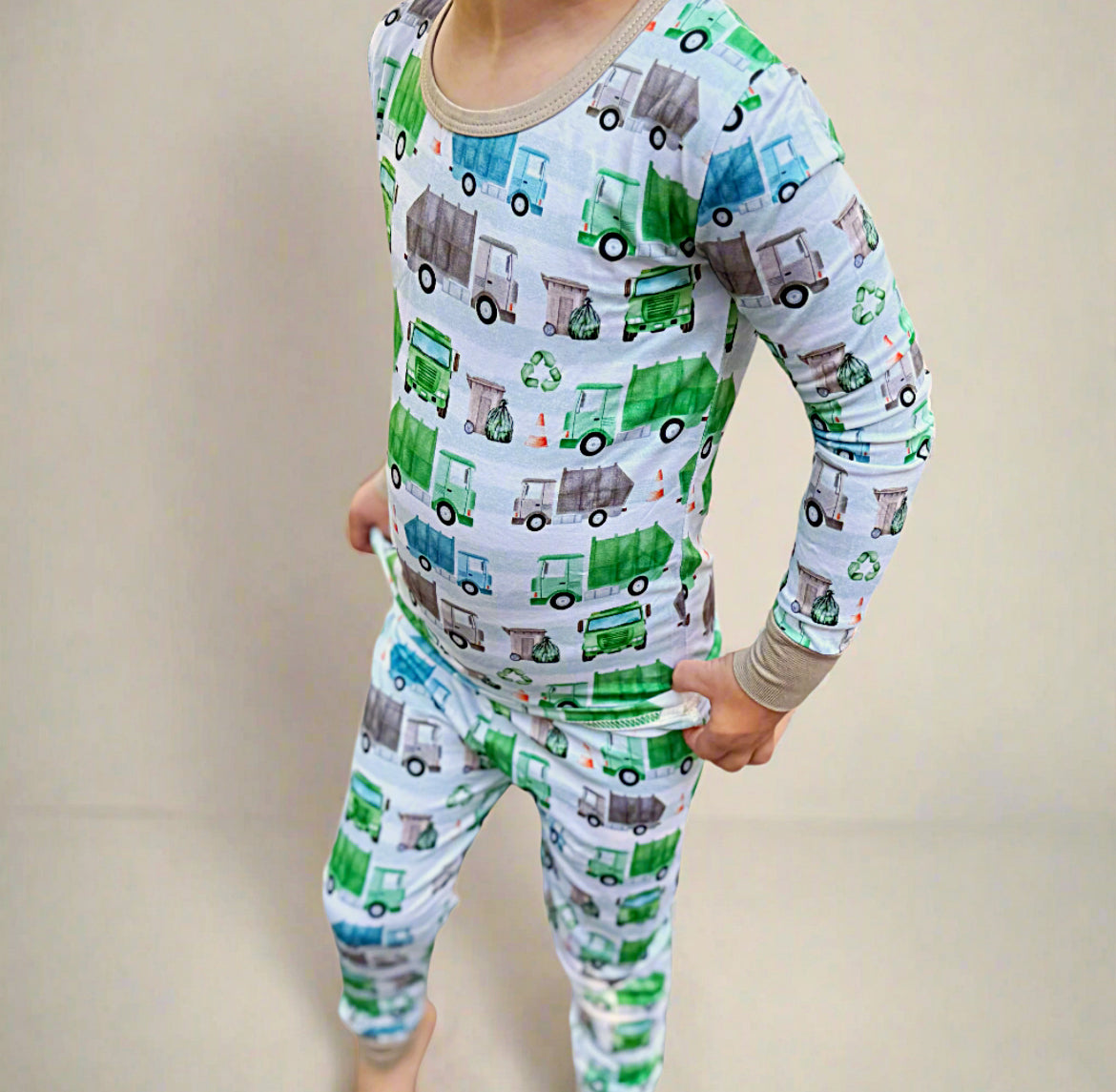 Child wearing pajamas with recycling truck pattern on a plain background