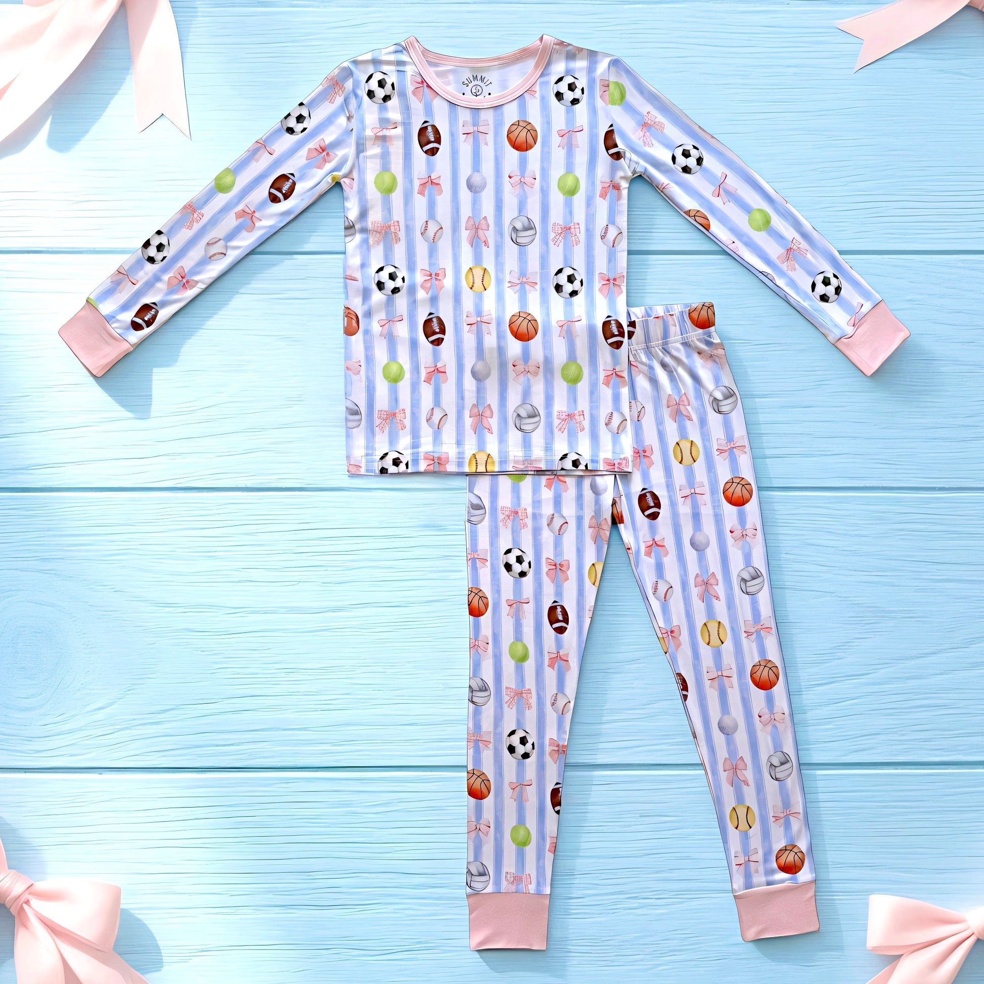 Children's bamboo pajama set with sports and bows  pattern on a blue wooden background
