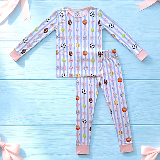 Children's bamboo pajama set with sports and bows  pattern on a blue wooden background