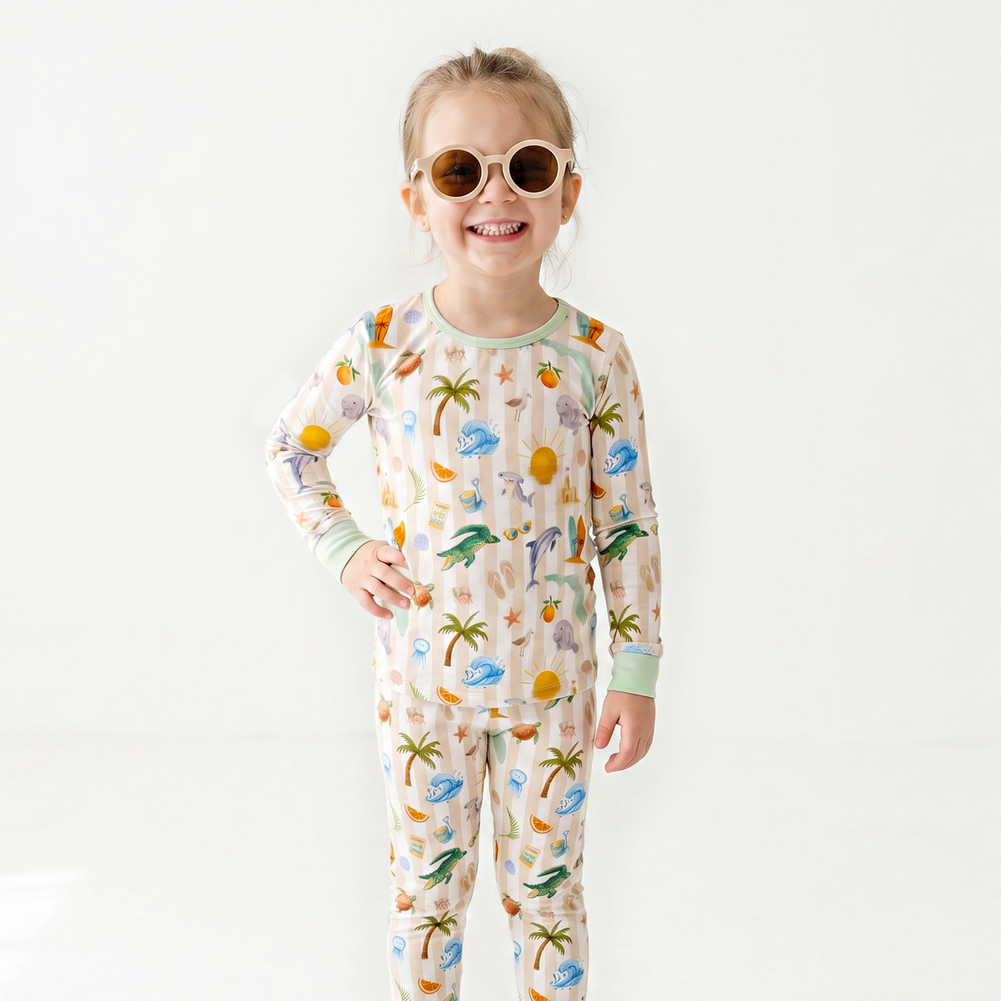 Child wearing a tropical-themed pajama set with sunglasses on a white background