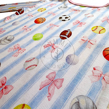 Fabric with sports-themed design featuring balls and bows on a striped background