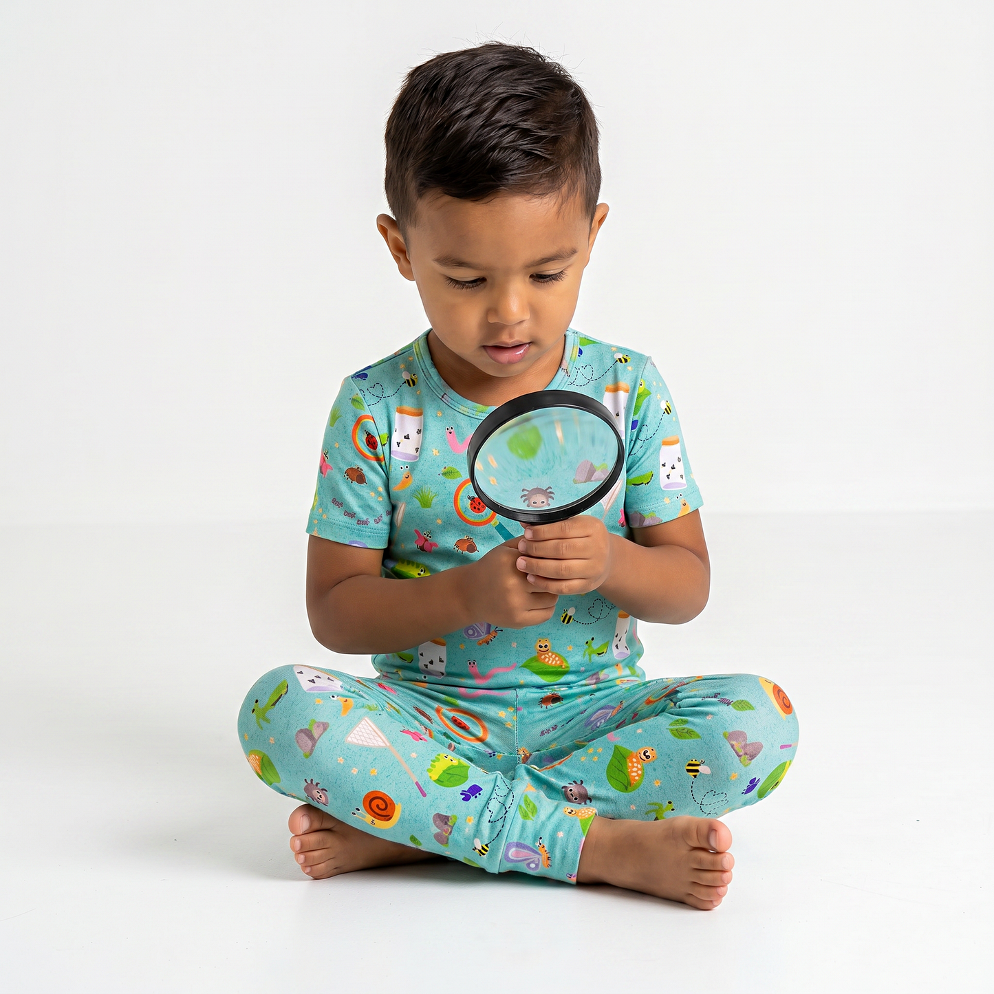 Child wearing a colorful outfit with a magnifying glass on a white background