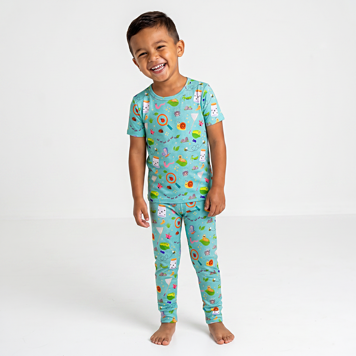 Child wearing a colorful bug pajama set with various patterns on a white background