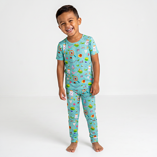 Child wearing a colorful bug pajama set with various patterns on a white background