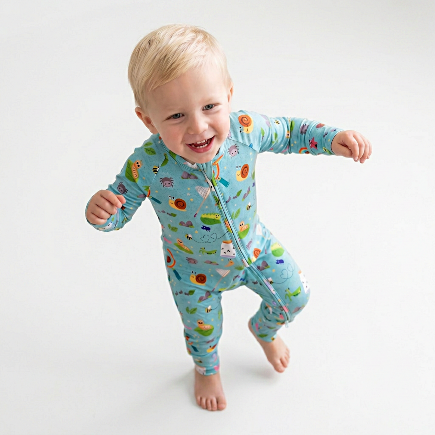 Child wearing a colorful pajama with bug patterns on a white background