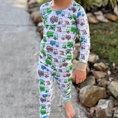 Child wearing pajamas with truck pattern standing outdoors.
