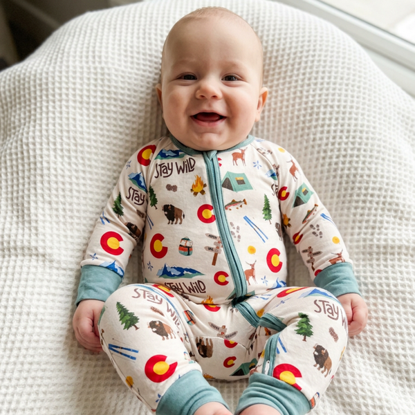 Baby wearing a Colorado onesie sitting on a textured surface.