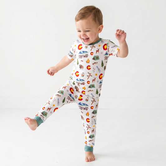 Child wearing a colorful pajama with colorado nature-themed designs on a white background