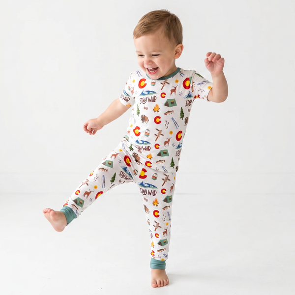 Child wearing a colorful pajama with colorado nature-themed designs on a white background