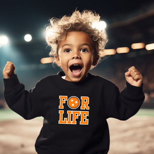 Child wearing a black sweatshirt with 'FOR LIFE' in orange letters, standing on a sports field.