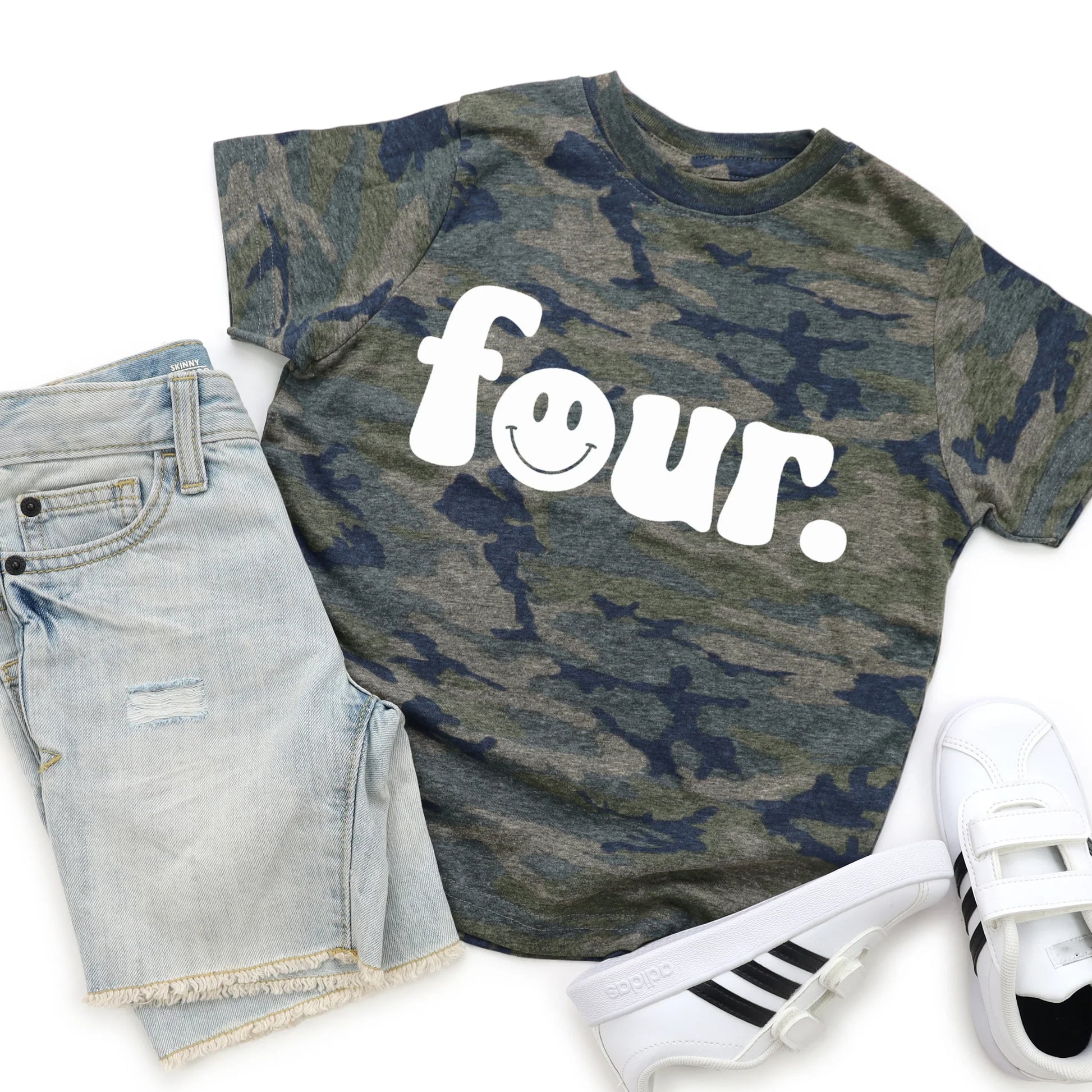 Camouflage t-shirt with 'four' print, denim shorts, and white sneakers on a white background