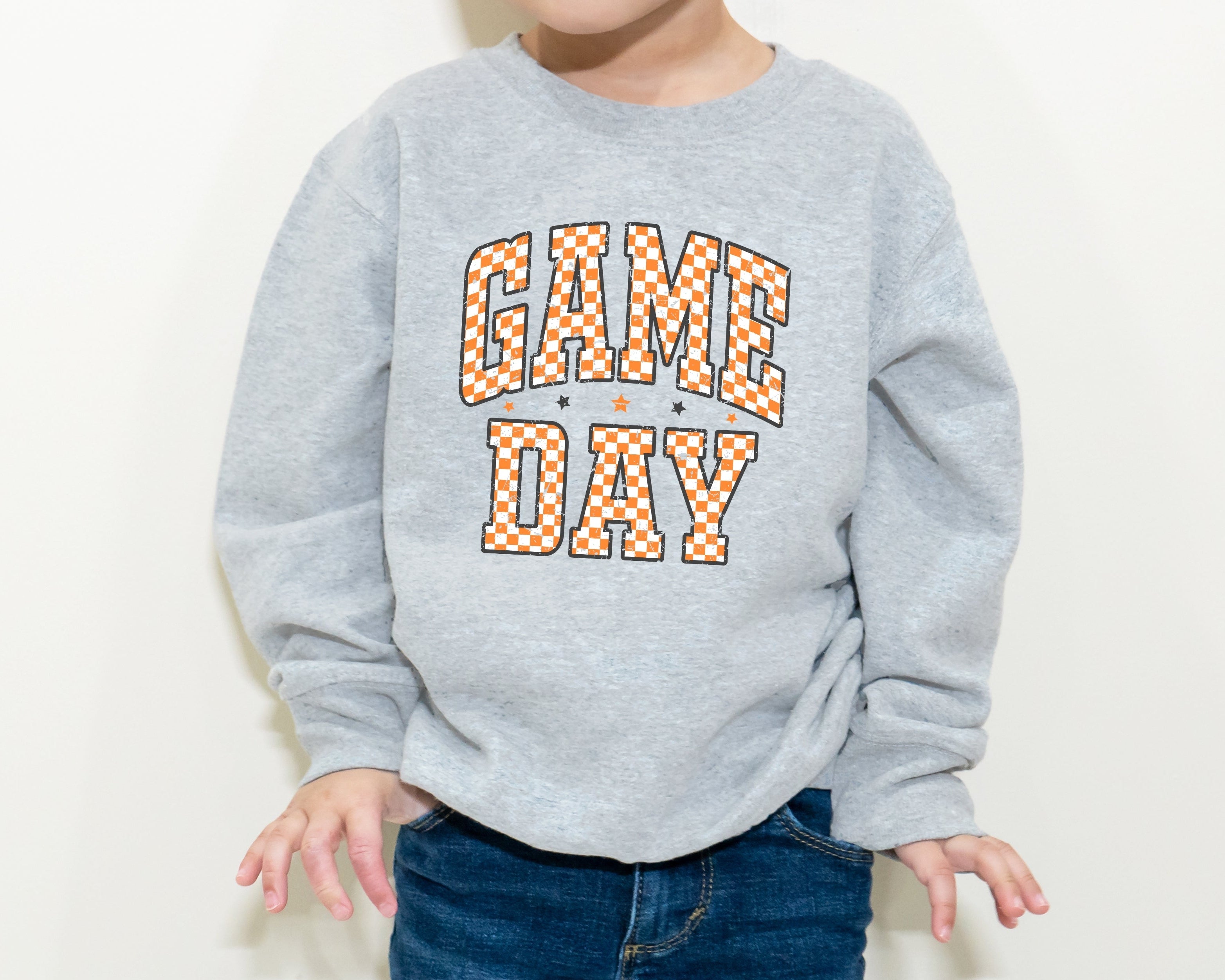 Child wearing a gray sweatshirt with 'GAME DAY' text on a white background