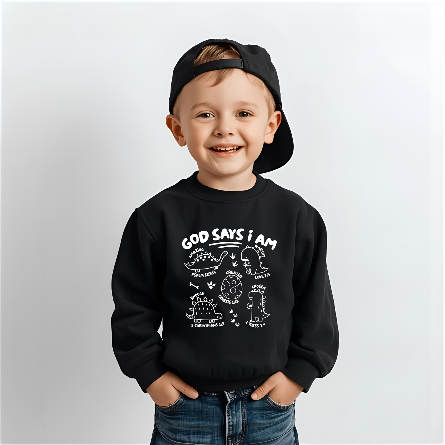 Child wearing a black sweatshirt with scripture faith- based text and dinosaur graphics on a plain background