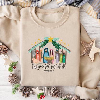 Beige sweatshirt with Christmas nativity scene design on a wooden surface with holiday decorations.
