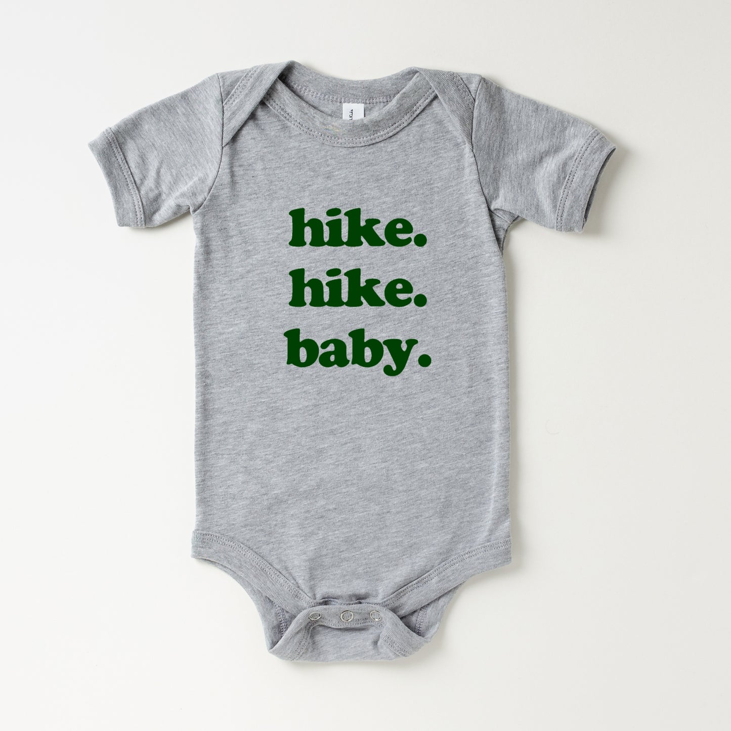 Gray baby onesie with green text 'hike. hike. baby.' on a white background