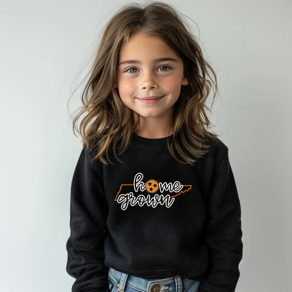 Child wearing a black sweatshirt with 'homegrown' text on a plain background