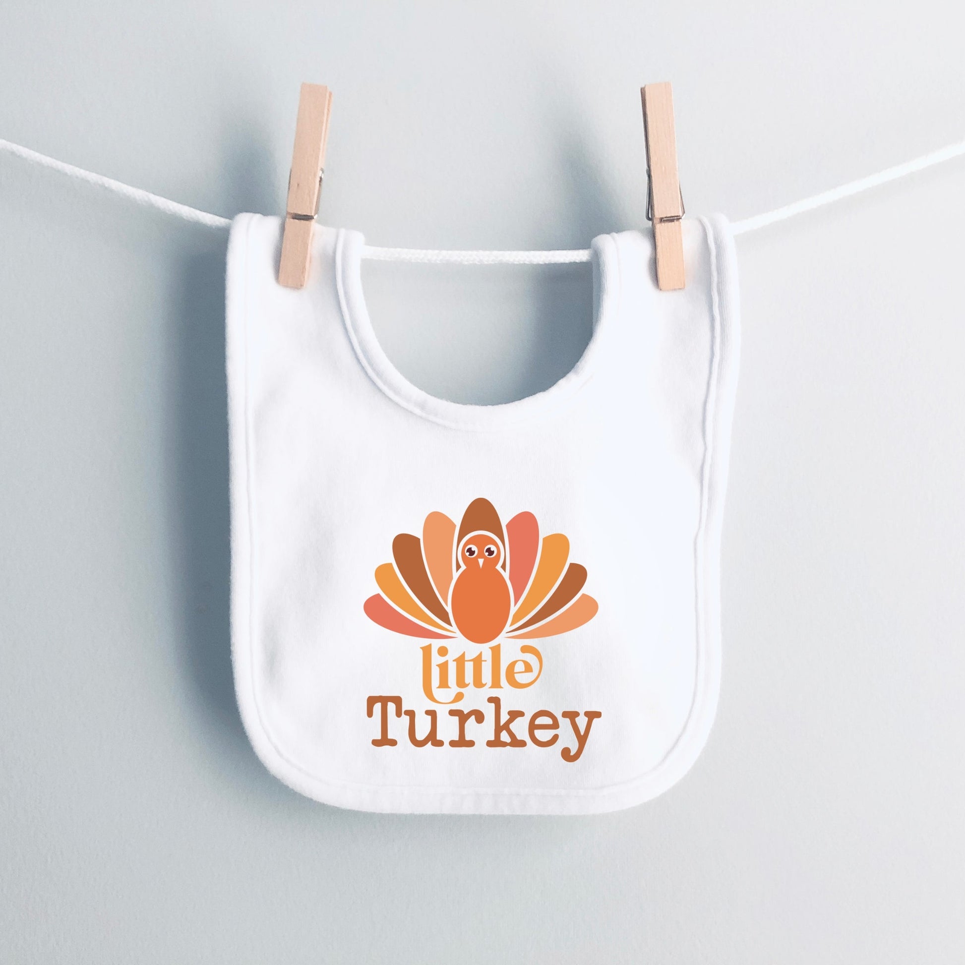 White bib with 'Little Turkey' design hanging on a clothesline.