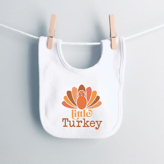 White bib with 'Little Turkey' design hanging on a clothesline.