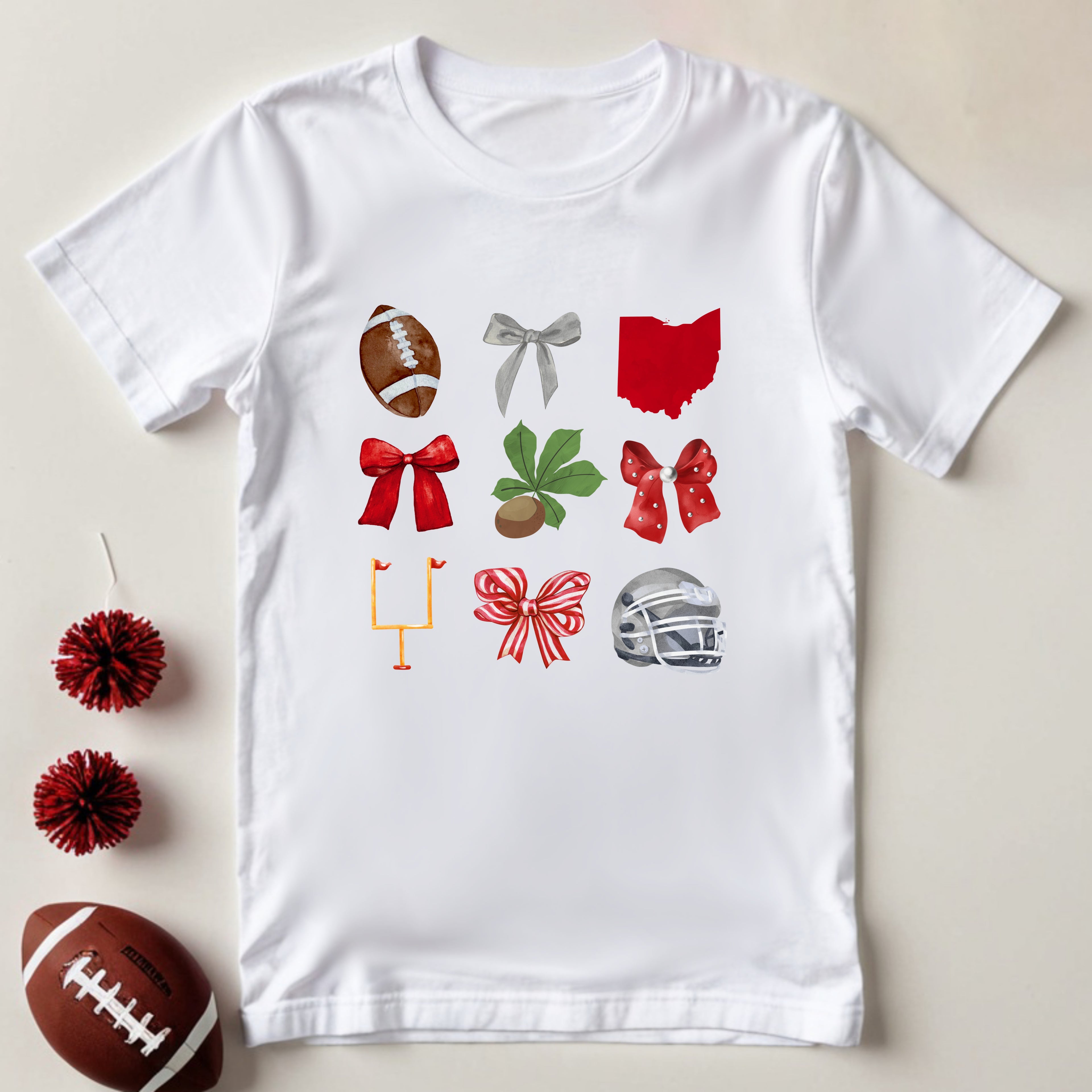 White t-shirt with sports-themed graphics on a beige background