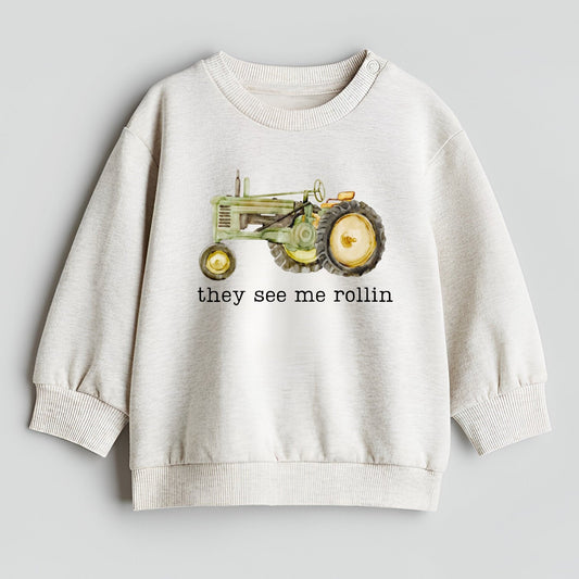 Children's sweatshirt with a tractor graphic and text on a light gray background