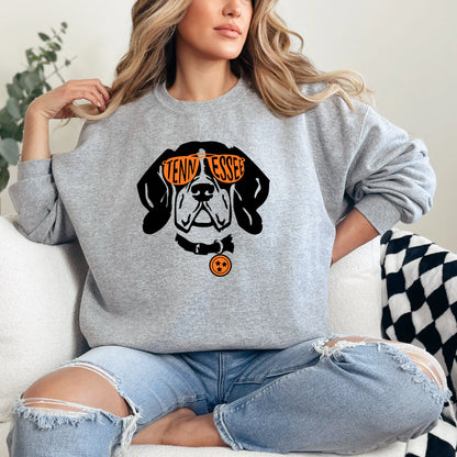 Person wearing a Vols gray sweatshirt with a dog graphic and text, sitting on a white couch.