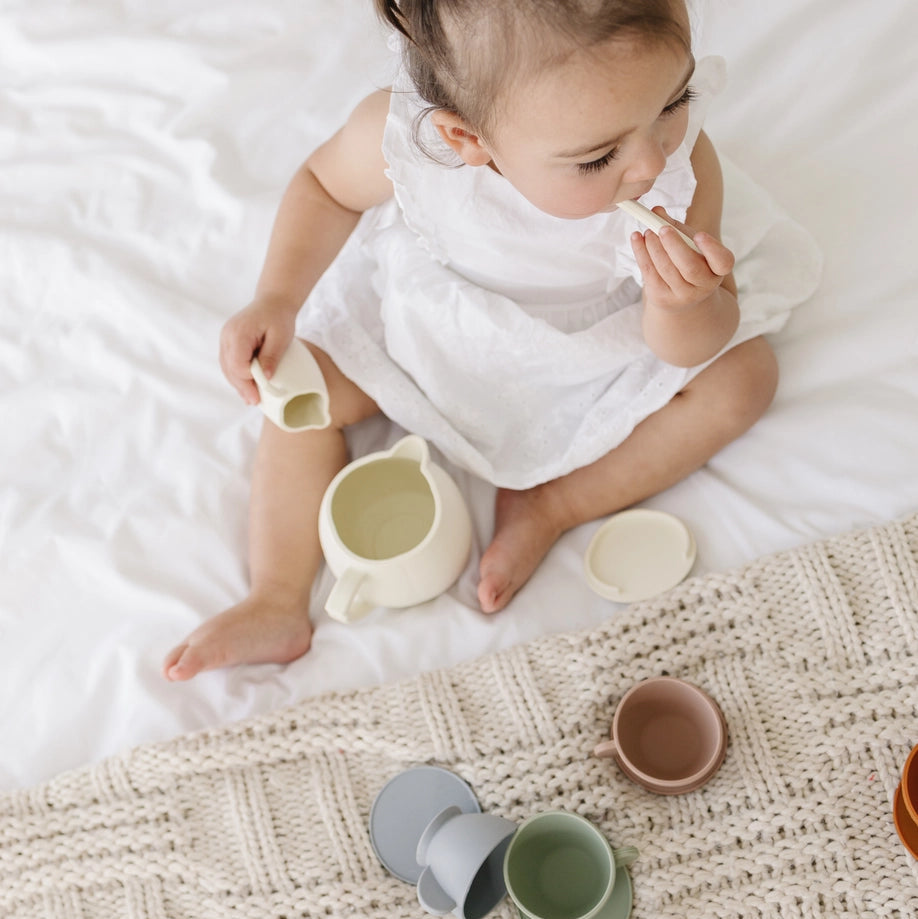 Child playing with silicone cups on a textured surface