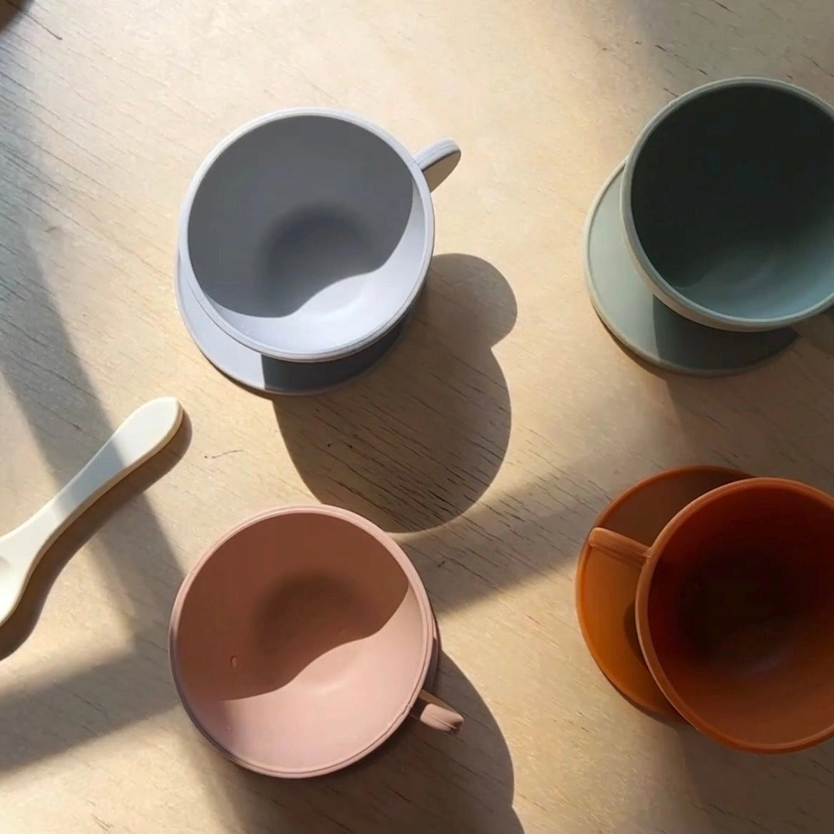 Set of colorful silicone tea set and a spoon on a wooden surface