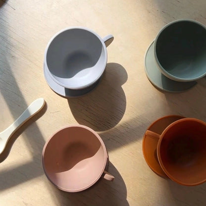 Set of colorful silicone tea set and a spoon on a wooden surface