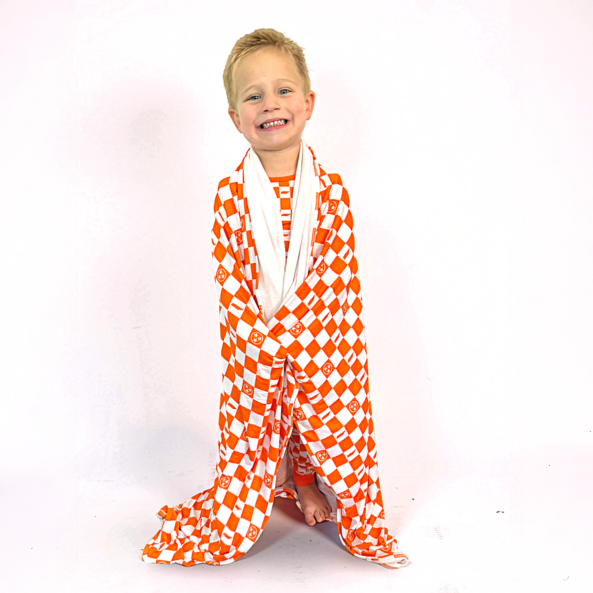Child wrapped in an orange and white checkered blanket on a white background