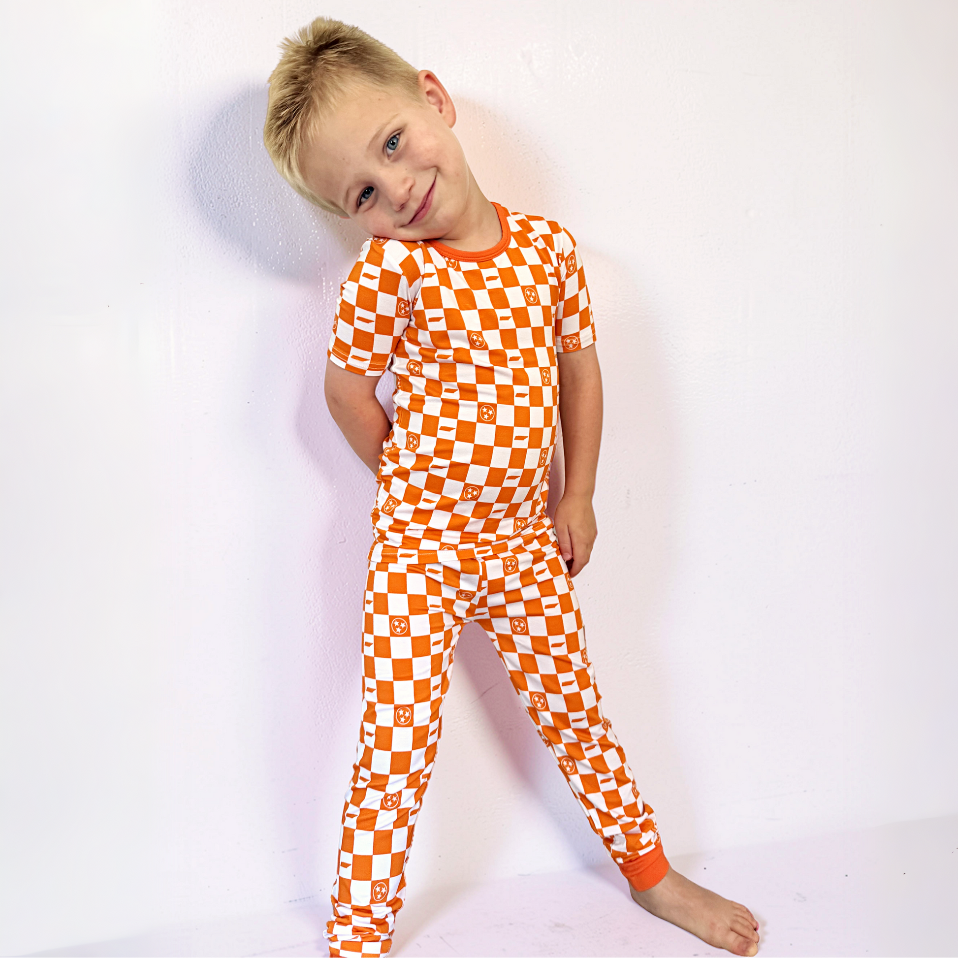 Child wearing an orange and white checkered outfit on a white background
