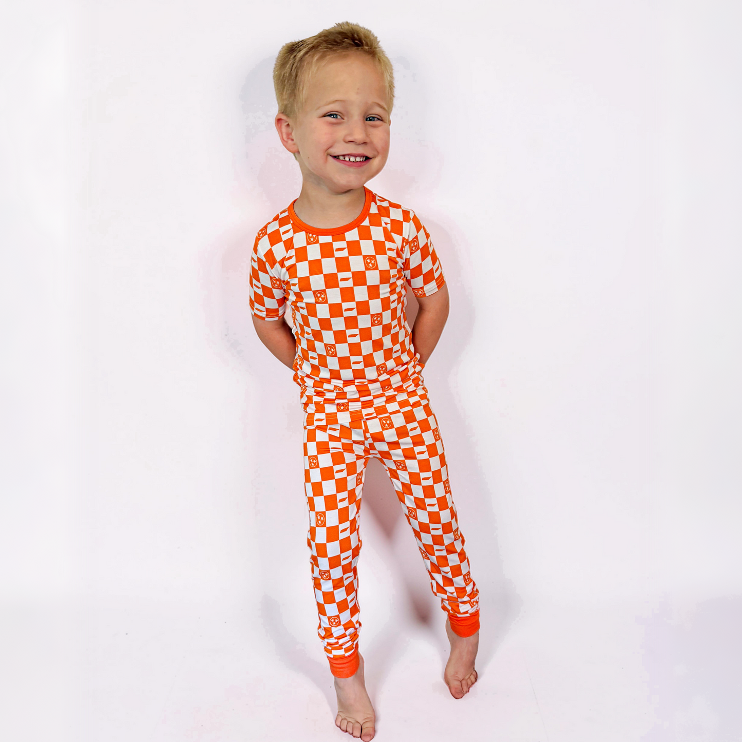 Child wearing an orange and white checkered onesie on a white background