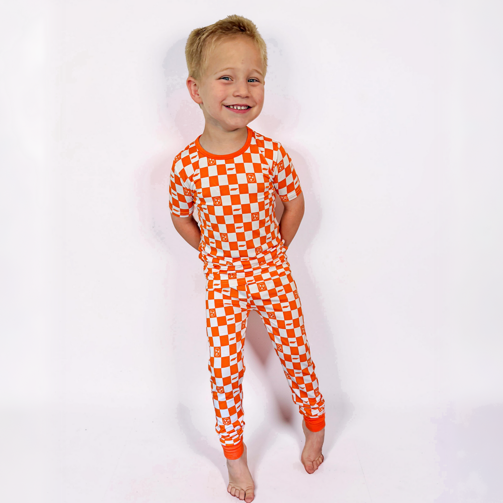 Child wearing an orange and white checkered onesie on a white background
