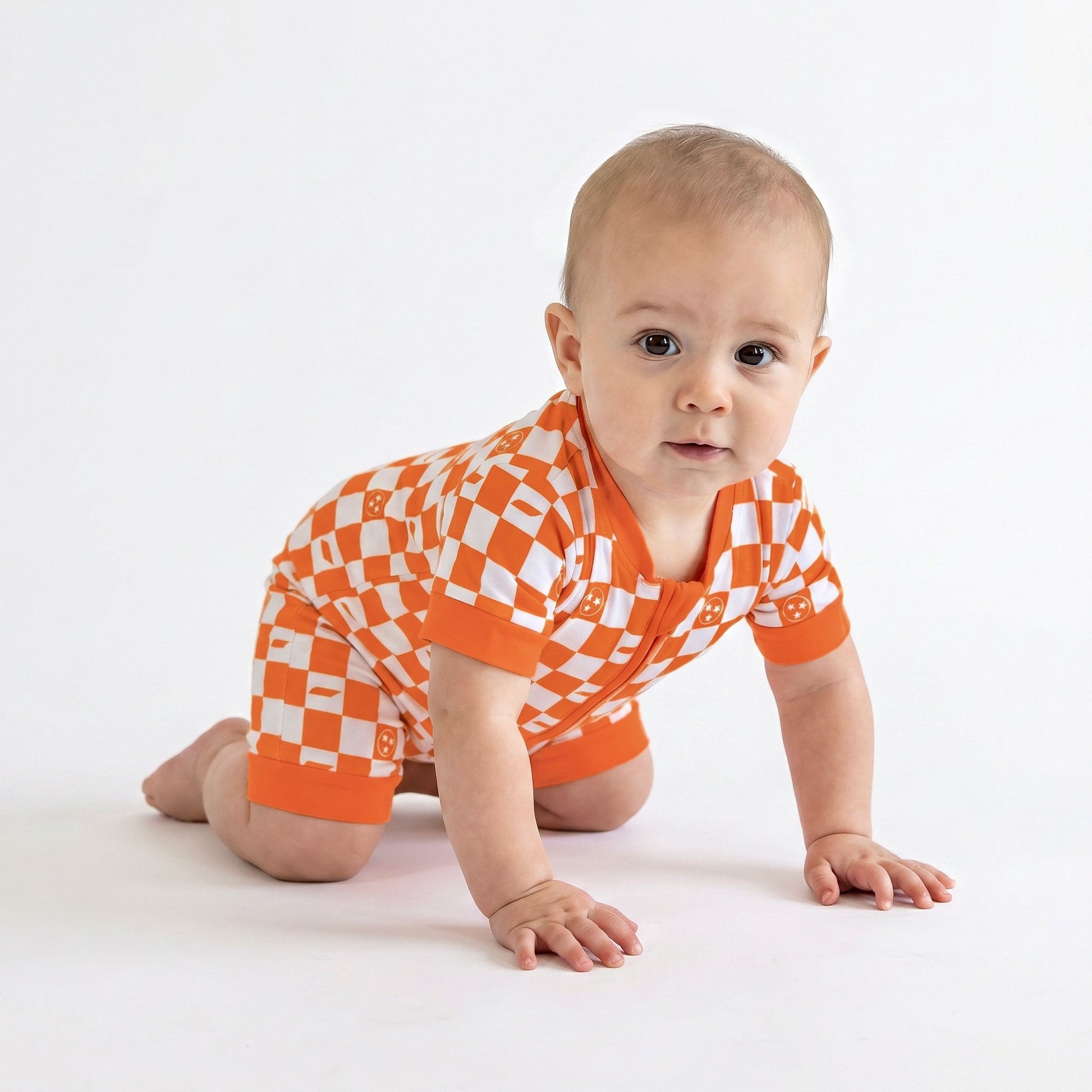Baby wearing an orange and white checkered outfit on a white background