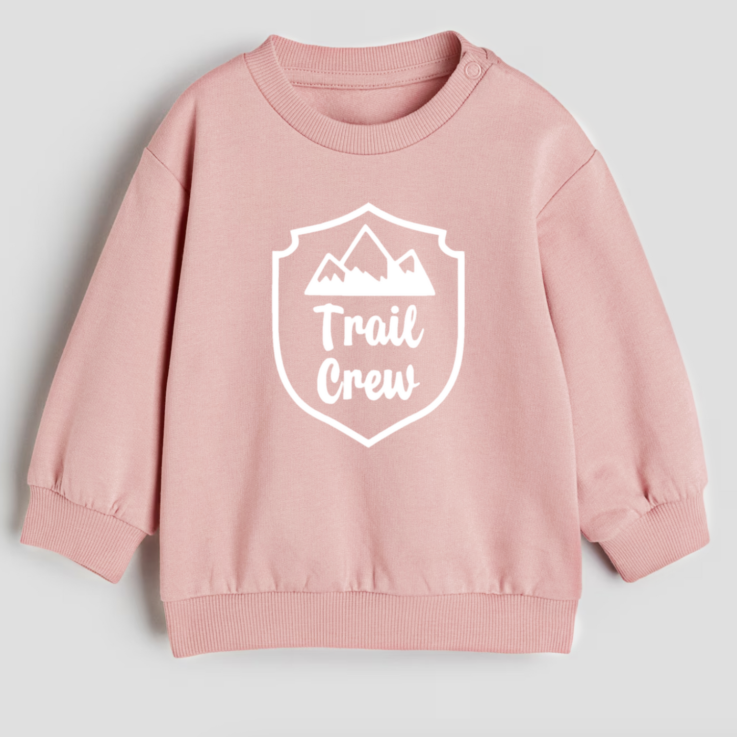 Pink sweatshirt with 'Trail Crew' logo on a light gray background