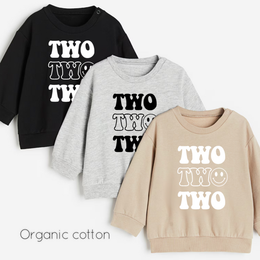 Three children's sweatshirts in black, gray, and beige with 'TWO' printed on them.